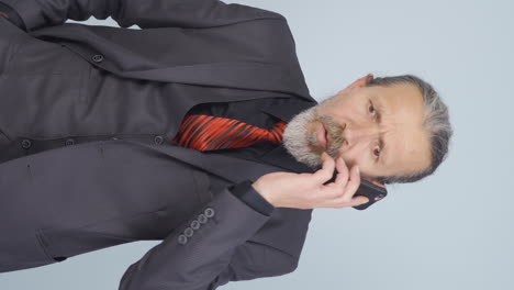 Vertical-video-of-Old-businessman-getting-interrupted-and-angry-while-talking-on-the-phone.